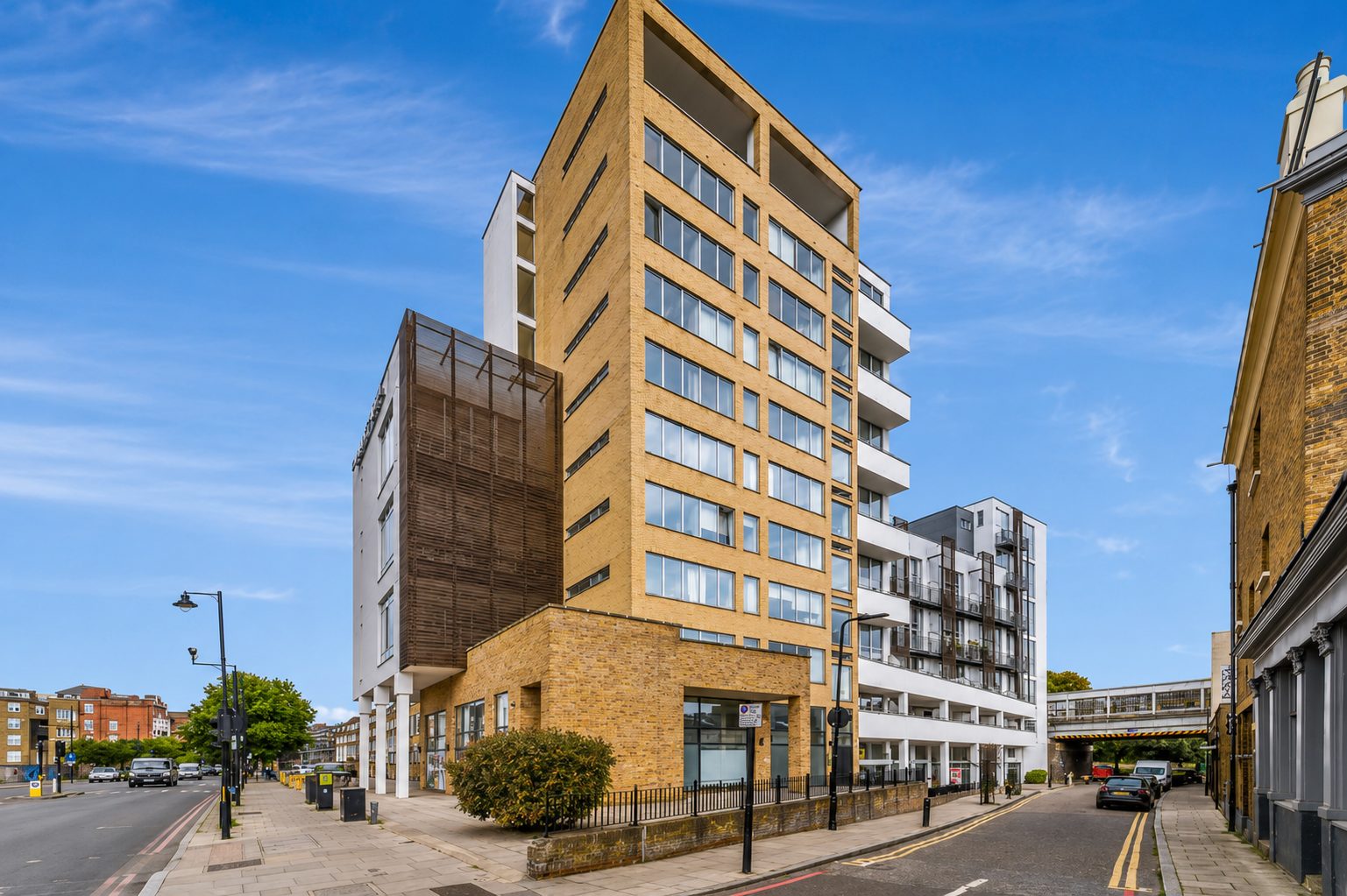 A brick residential tower within Ability Plaza's wider Kingsland Road site, its balconies screened in dark timber-effect panelling