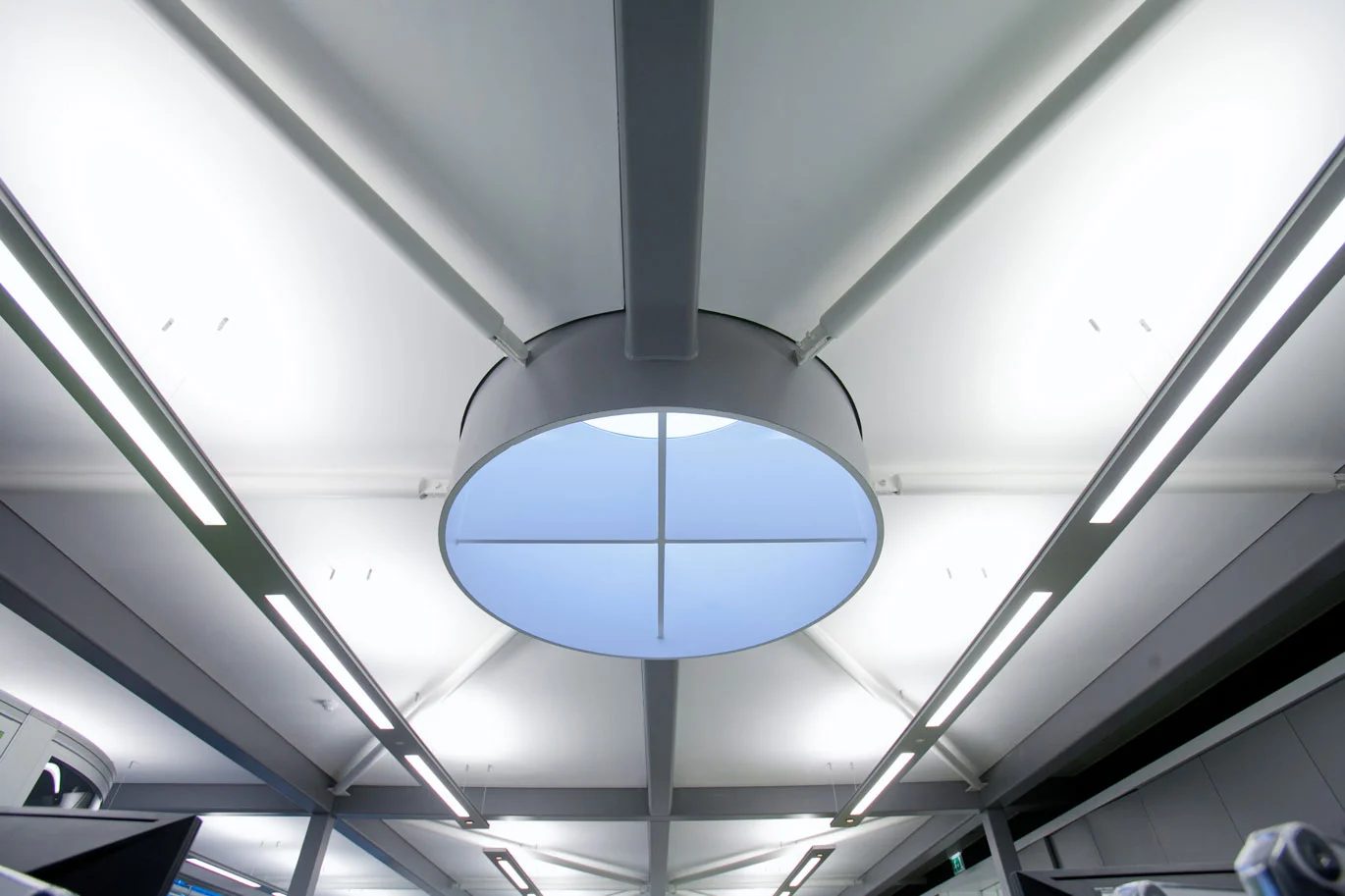 A circular rooflight in the exposed steel roof structure of Ashfield House's rooftop pavilion, seen from below
