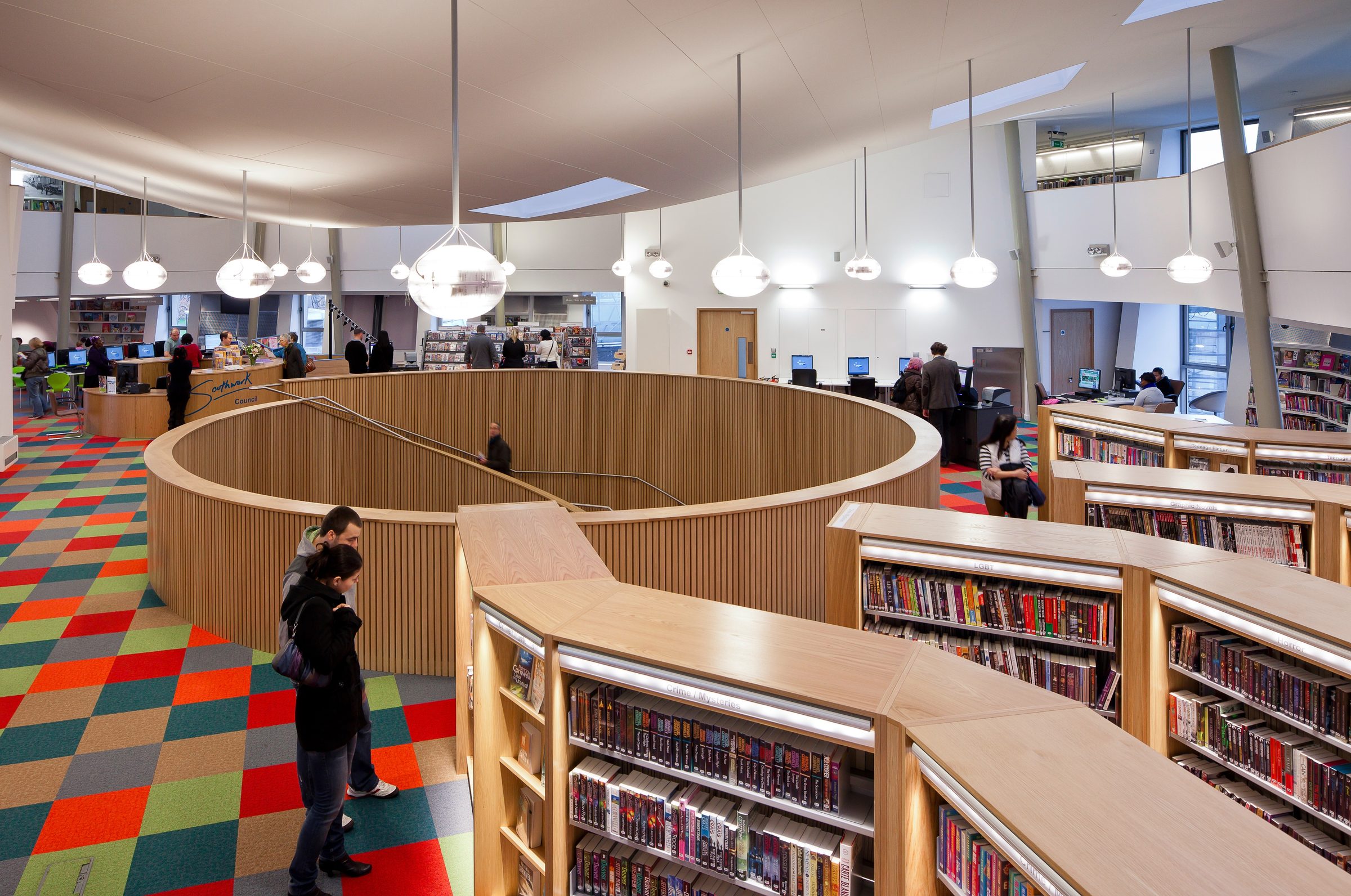 Canada Water Library's circular ground floor, book stacks curving around the base of the helical stair
