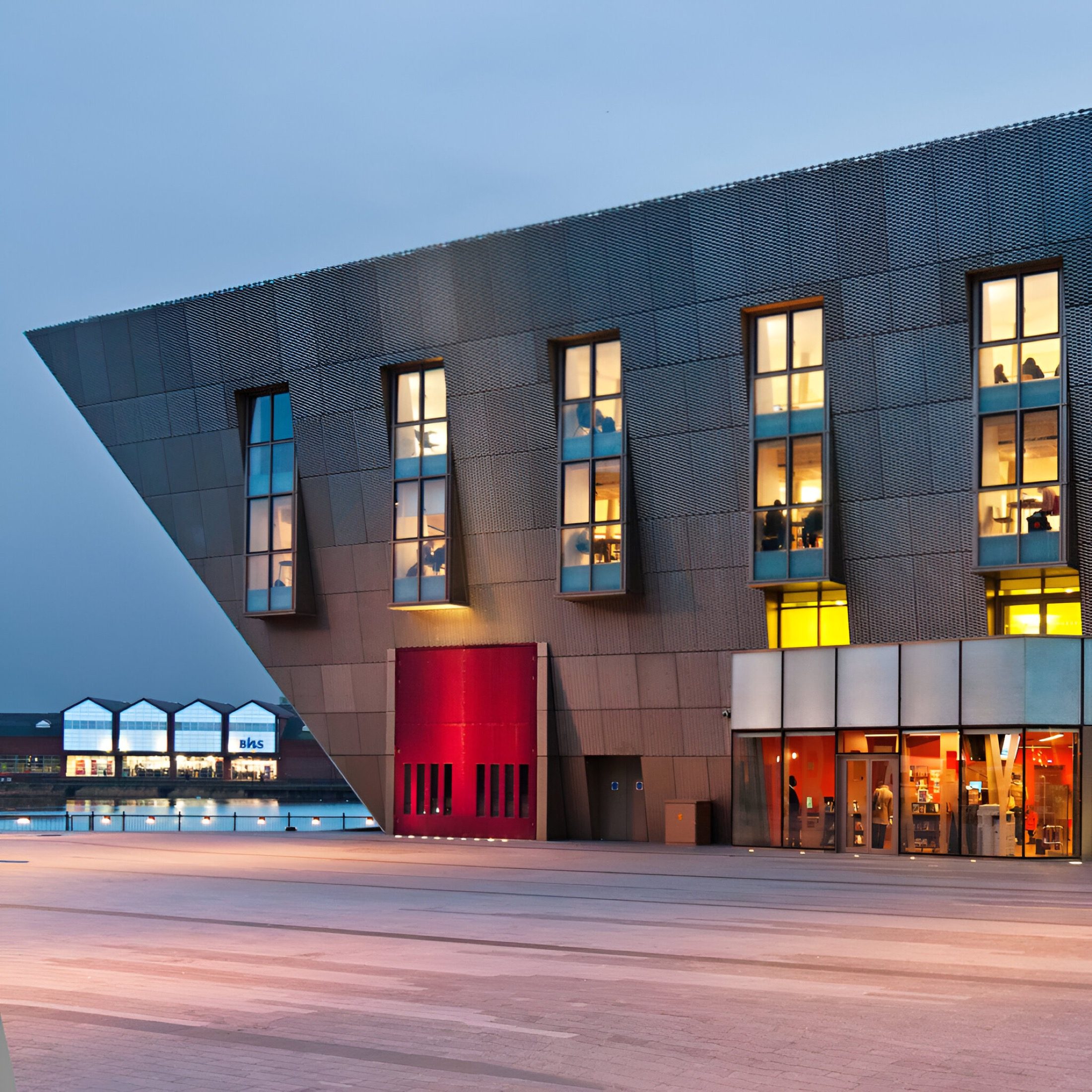 Canada Water Library at dusk with the interior lit behind the angled first-floor windows