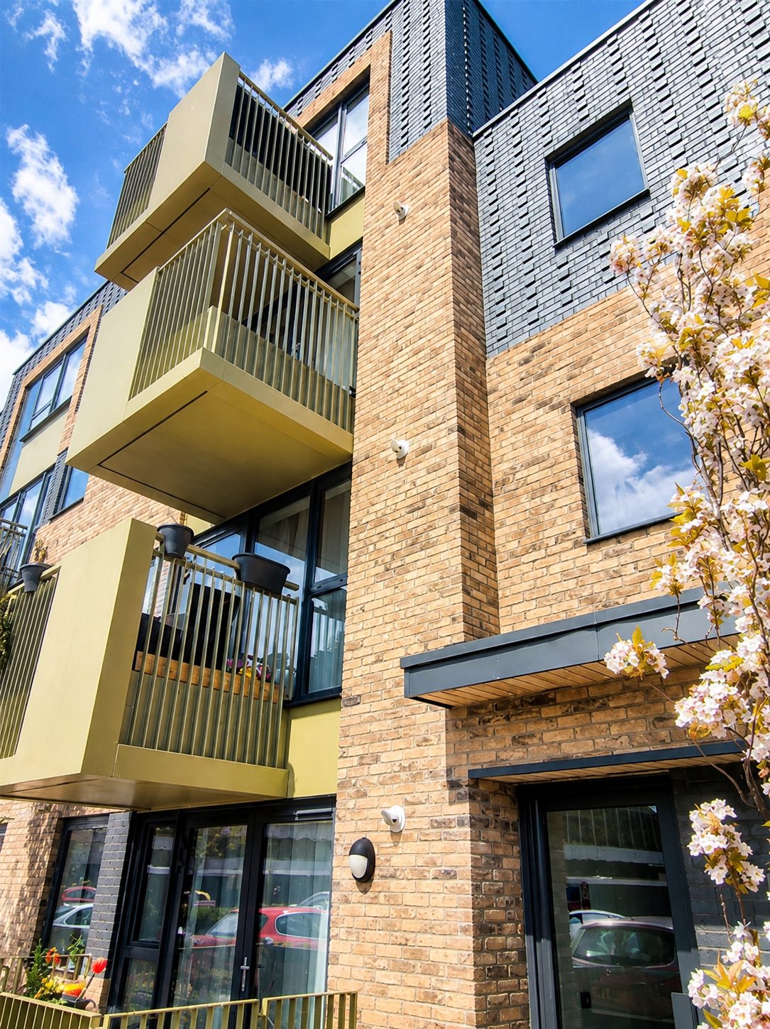 Close view of stacked gold-finished Cassette balconies above a ground-floor entrance door at Carnarvon Road