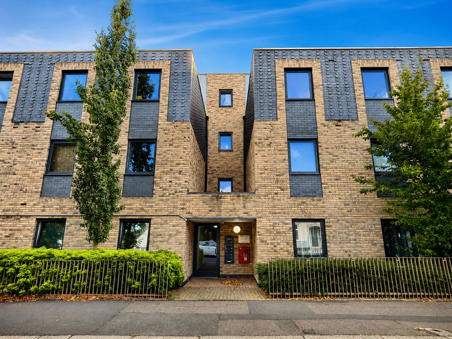 Front elevation of an apartment block on Carnarvon Road with a recessed entrance porch between two brick and dark-tile gables