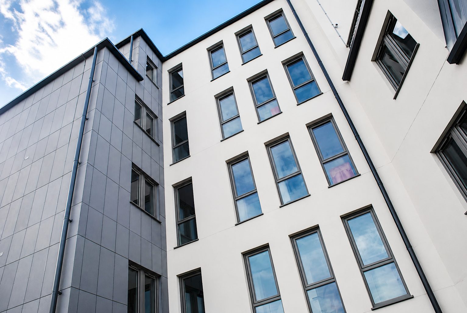 Illustration of grey fibre-cement rainscreen panels meeting off-white render and grey-framed windows at Ciceley Court, Stafford Road, Croydon