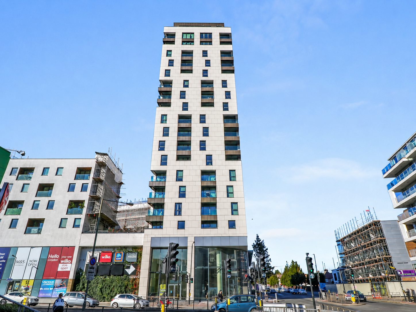 Everly House's completed street-level frontage in Colindale, with ground-floor retail glazing and traffic passing on Edgware Road