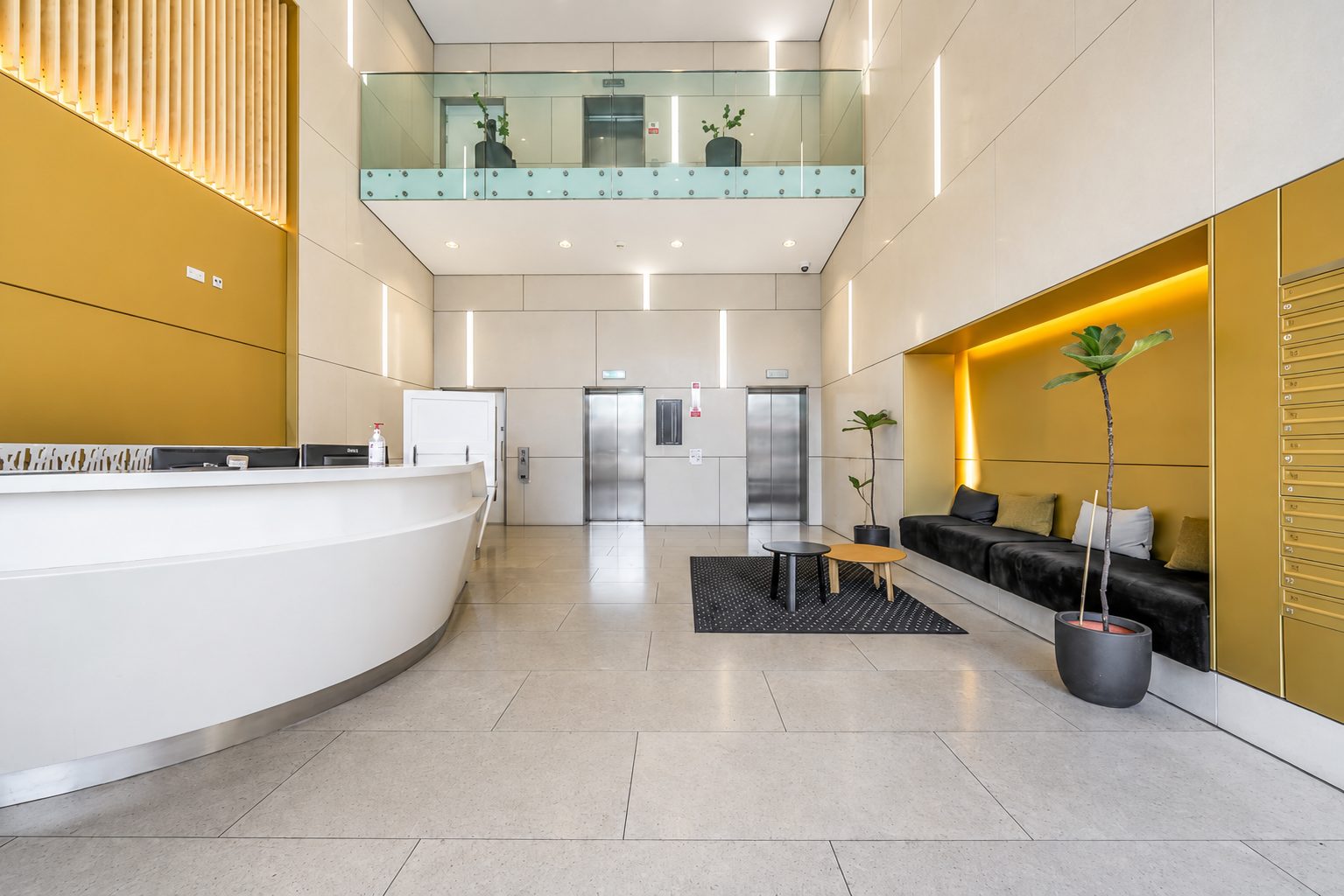 The entrance lobby at Everly House, with a curved reception desk, lift lobby and mailboxes beneath a double-height ceiling