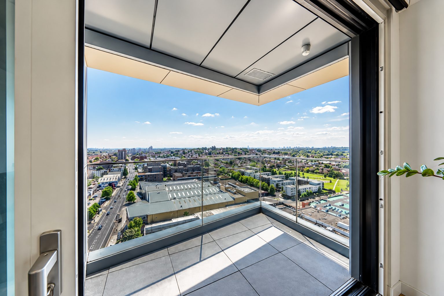 A corner balcony at Everly House with glazed balustrade and aluminium soffit, overlooking Colindale rooftops