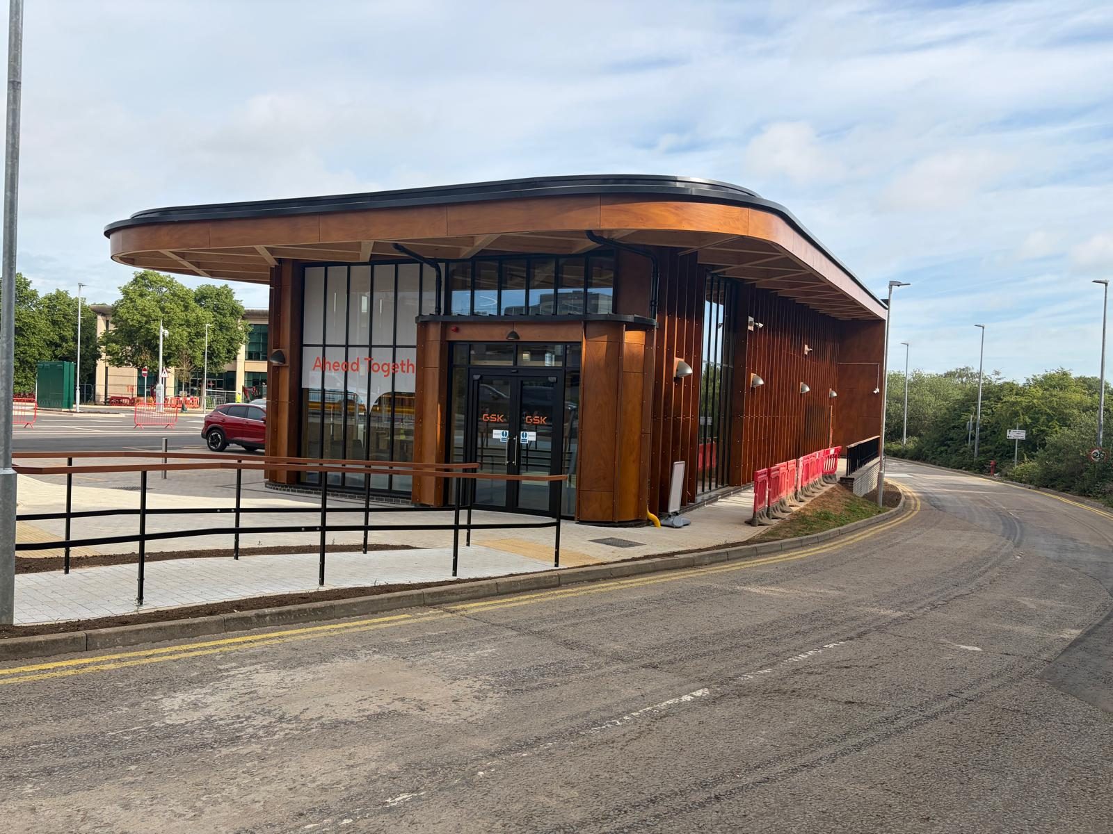 The GSK Security Lodge in Stevenage, its curved timber-faced canopy and vertical fins framing the glazed entrance