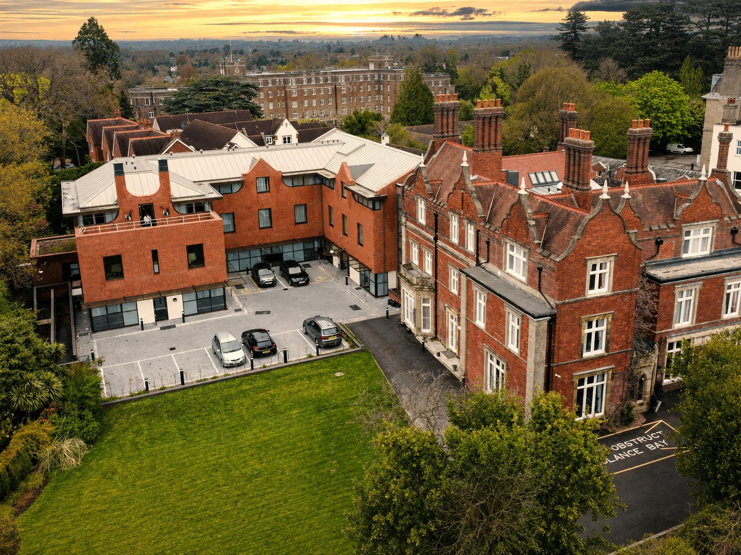 Aerial view of Mount Ephraim House at dusk, the historic red-brick house beside its extension with a pale standing-seam roof and roof terrace