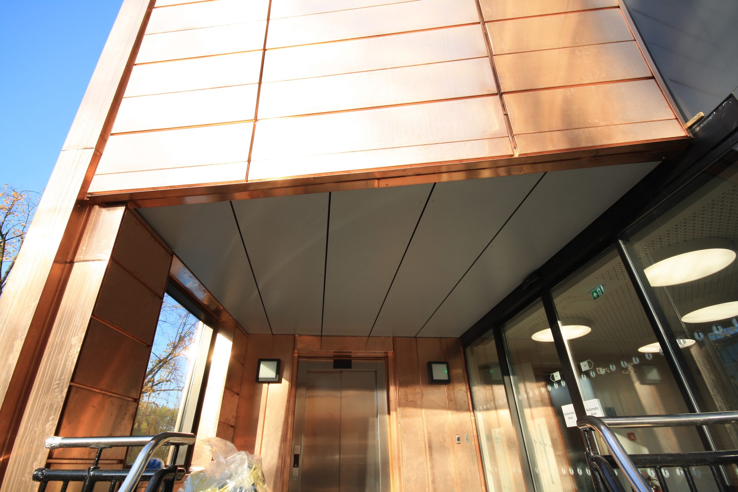 Copper-clad entrance porch and lift lobby at Putney High School, with automatic glazed doors