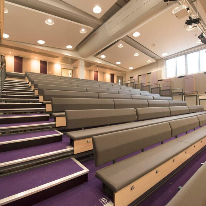 The completed auditorium interior at Putney High School's Performing Arts Centre, with tiered seating on purple carpet