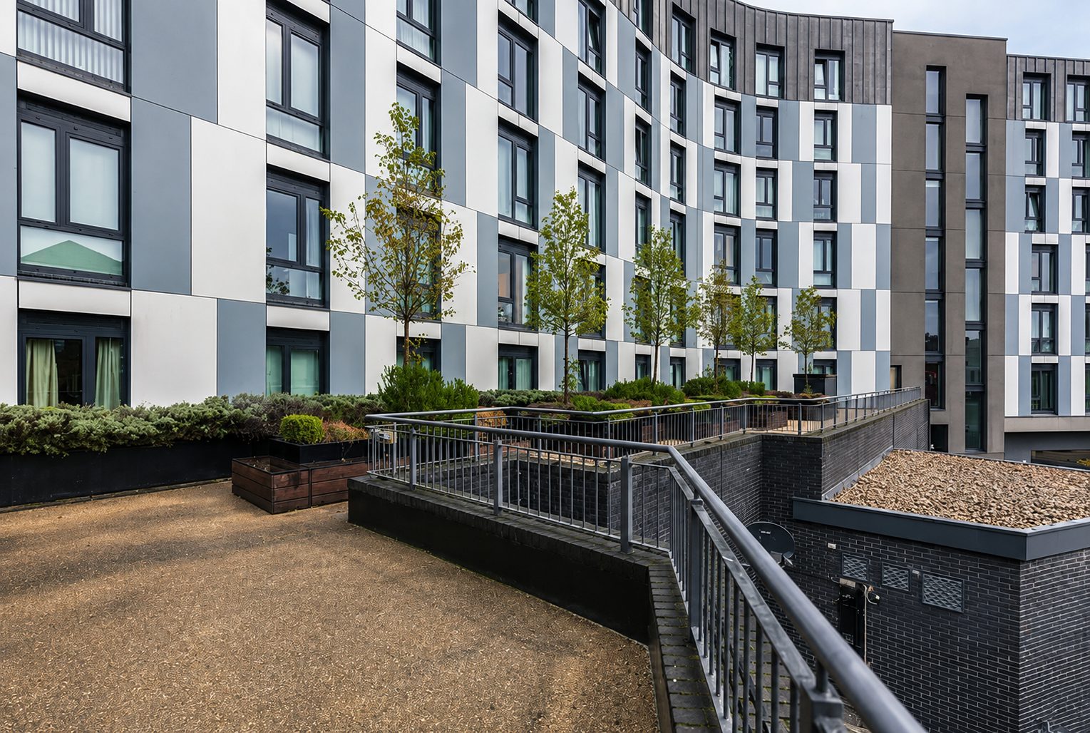 Roof terrace walkway at Nobel House with planting and railings, town rooftops beyond