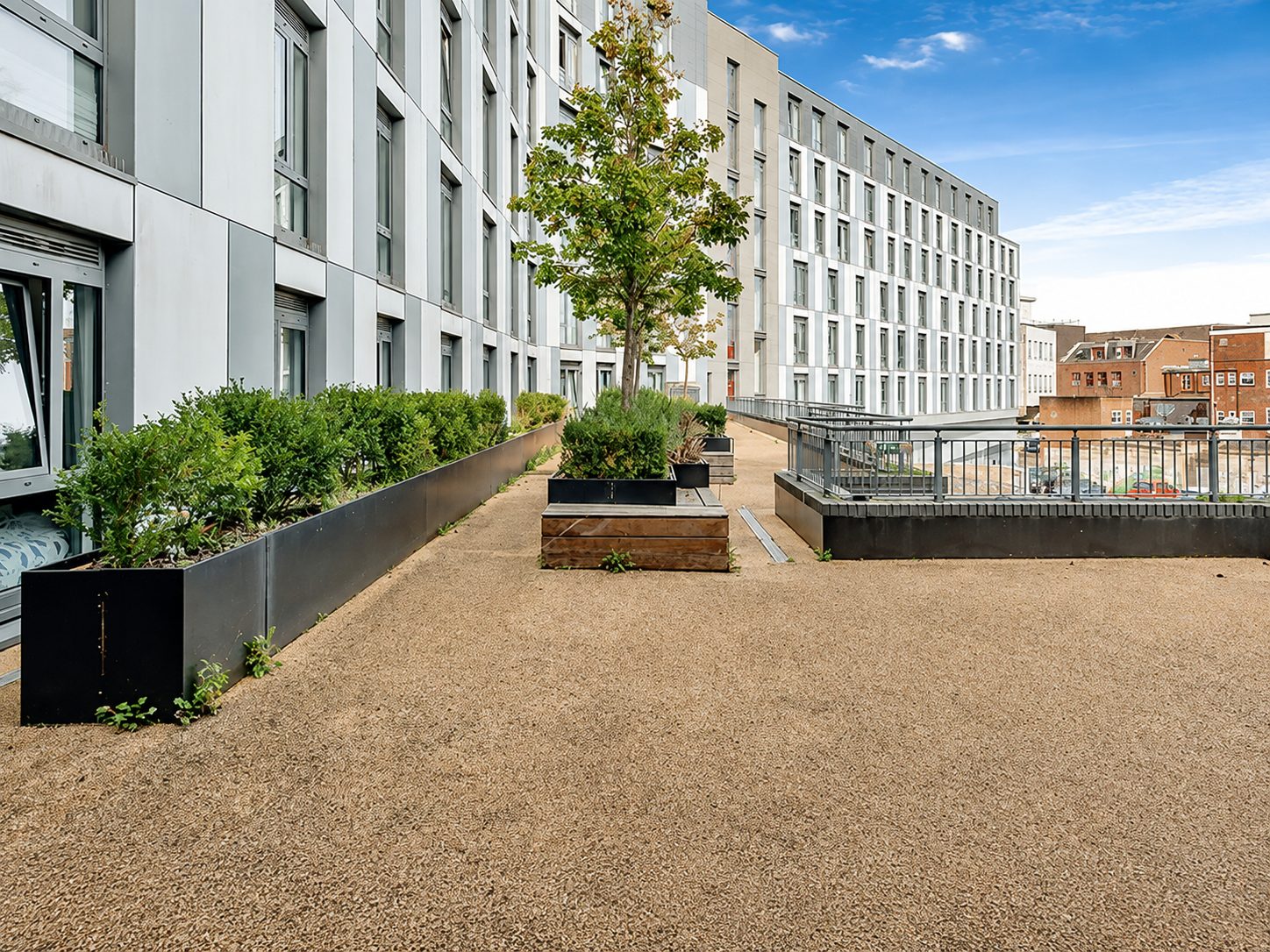 Wide view of Nobel House's curved corner, pale grey upper floors above orange timber-effect cladding, Redhill