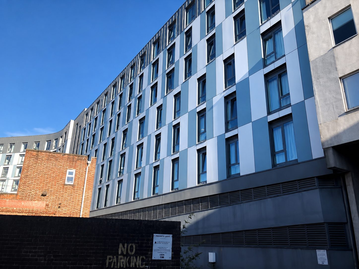 Nobel House's blue-grey cladding panels beside a red-brick neighbouring building in Redhill