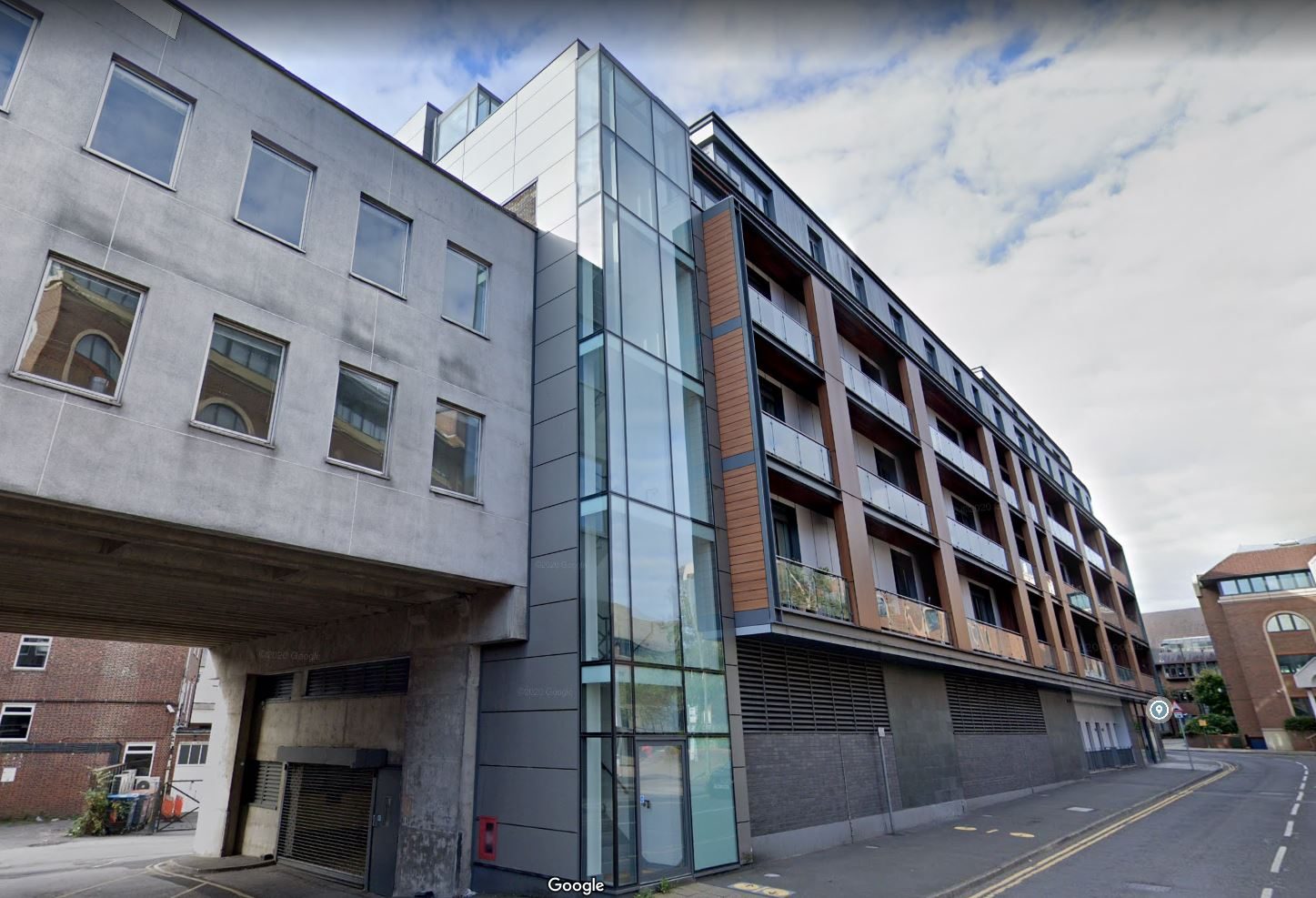 Nobel House's glazed corner stair tower and orange rainscreen cladding above an elevated road in Redhill