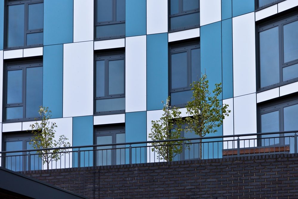 Close view of blue and white cladding panels meeting window and balcony openings at Nobel House