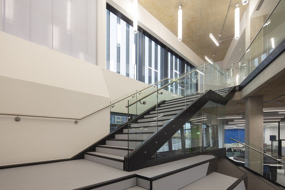 The glazed atrium stair inside the Centre for Digital Technologies, rising through the building's three storeys under an exposed concrete soffit