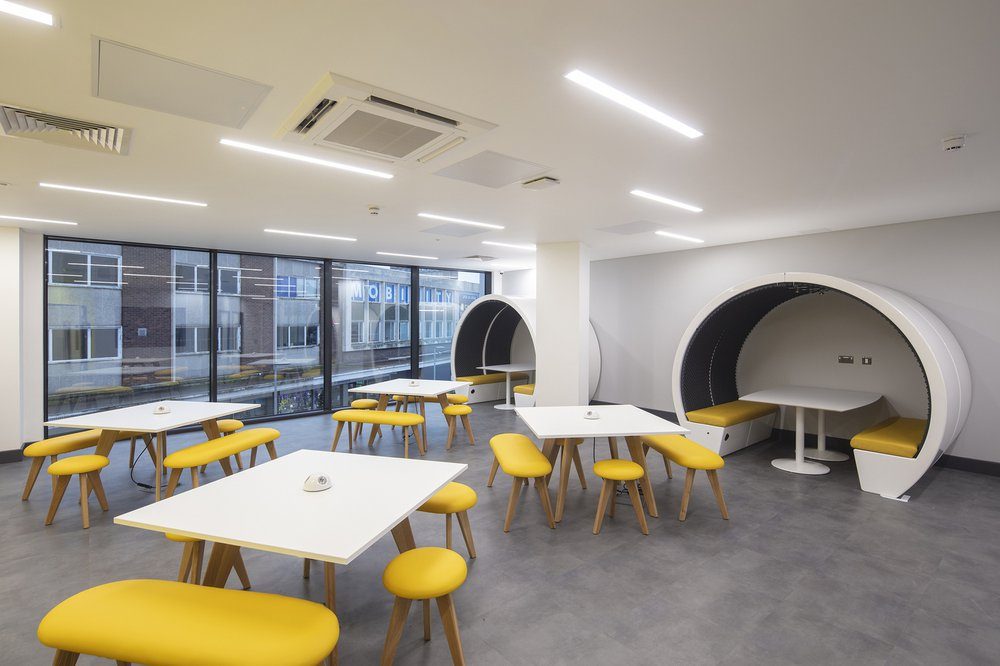 A student breakout space inside the Centre for Digital Technologies, with yellow furniture and enclosed pod seating for group work