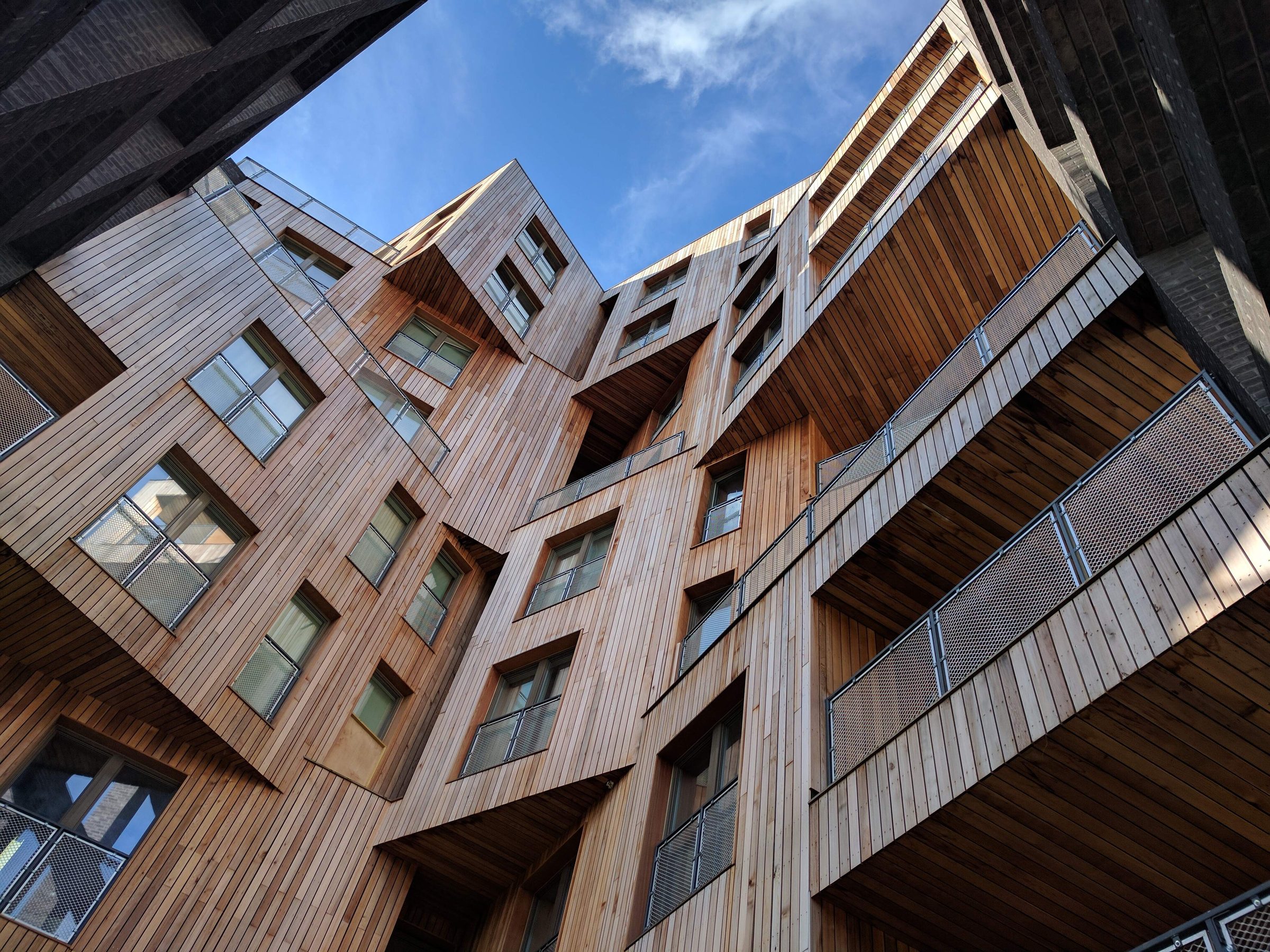 Upward street-level view of The Cube's cedar-clad elevation, photographed in March 2017