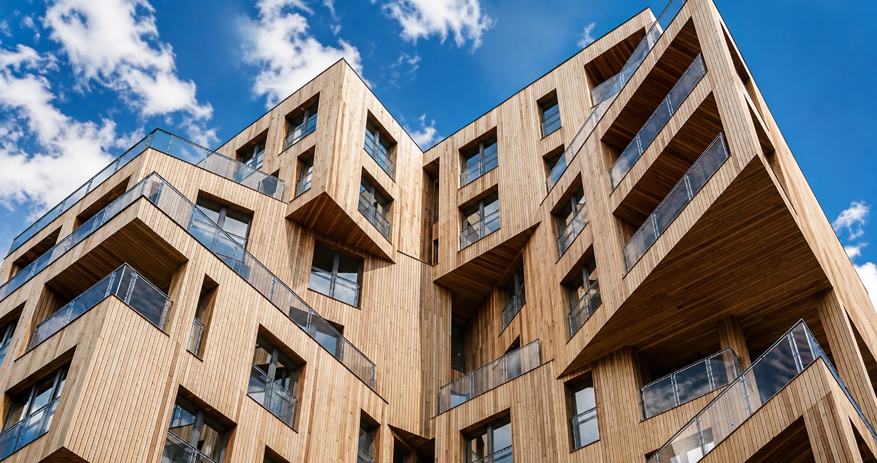 Low-angle view of The Cube's cedar-clad upper storeys and balconies against a blue sky