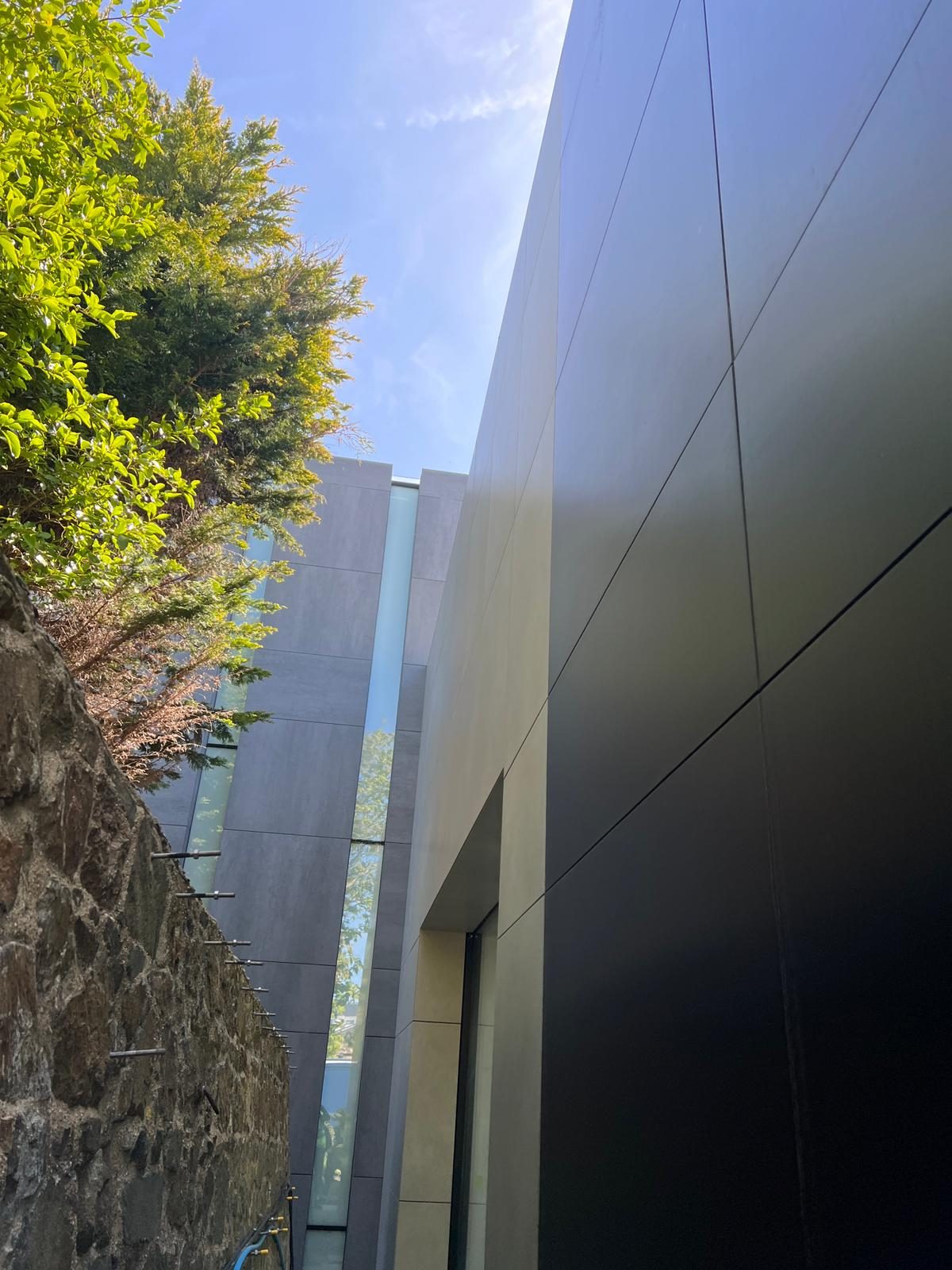 A dark feature cladding panel meeting lighter grey engineered stone panels at a sharp building corner at The Lighthouse