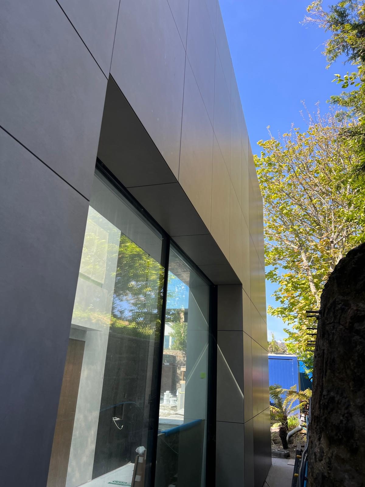 A window reveal cut into The Lighthouse's stone panel run, where the panels return to a warmer-toned finish at the building corner