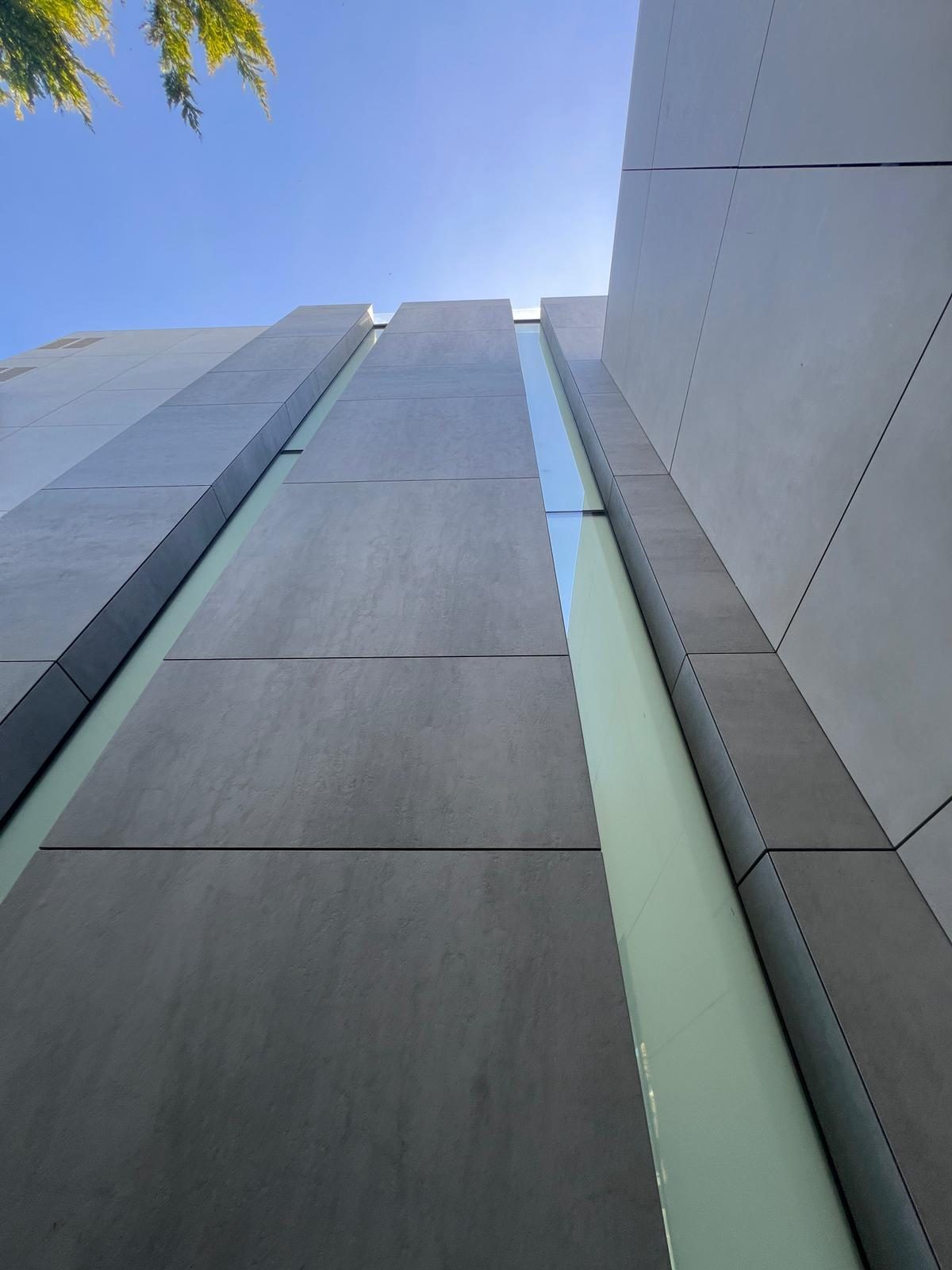 Close view of a vertical light-channel joint between two grey engineered stone panel runs at The Lighthouse