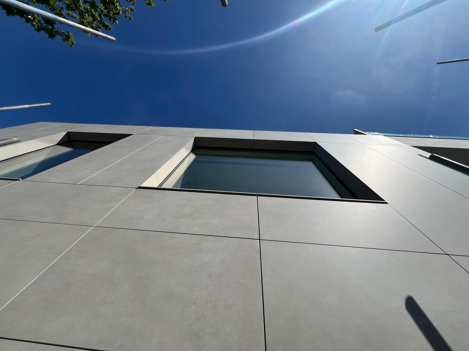 A window reveal cut into The Lighthouse's engineered stone panel run, seen looking straight up from below