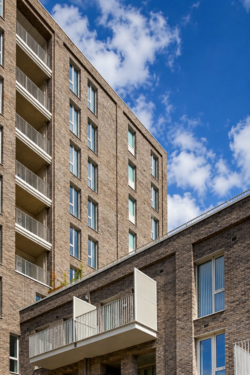 Close view of brick and stone facade detailing where The Refinery’s tower meets its lower five-storey block