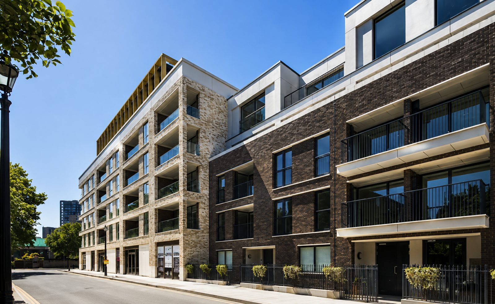 Trilogy's Harper Road corner in daylight, ground-floor glazing beneath brick-clad upper floors and a gold-toned roof loggia