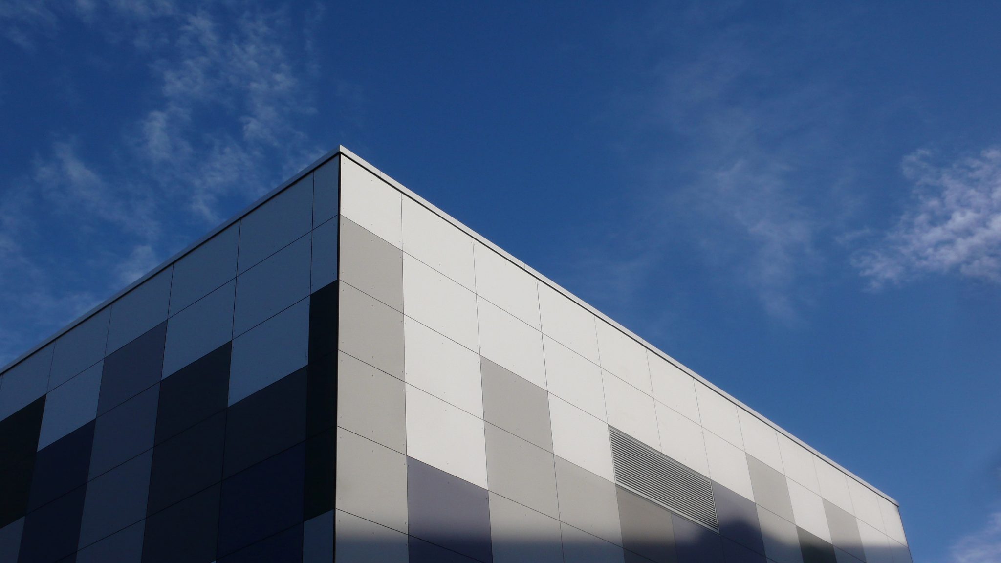 Close view of dark grey and near-black Eternit Pictura fibre-cement cladding panels at another corner of a building at Vodafone's Swindon data centre, graduating toward pale panels above